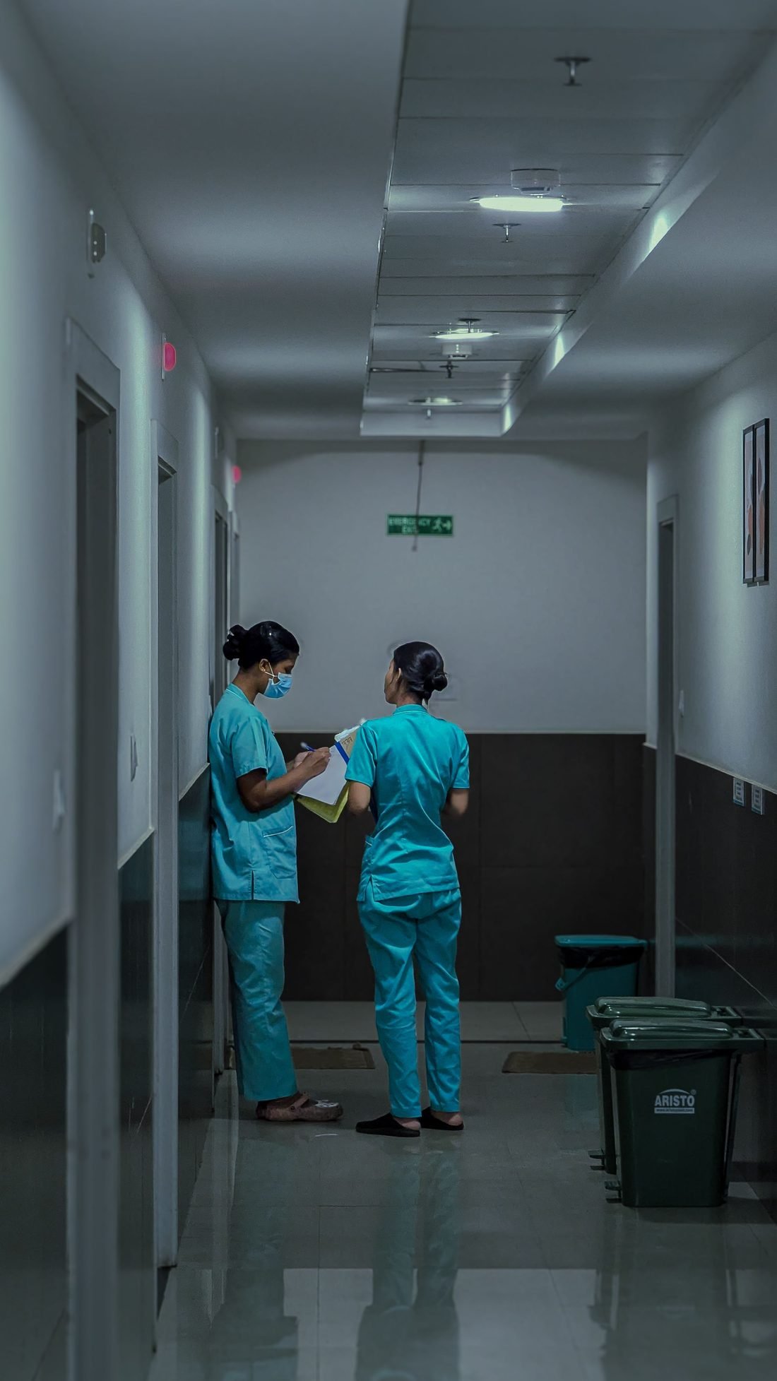 Two nurses going over notes in a hospital corridor